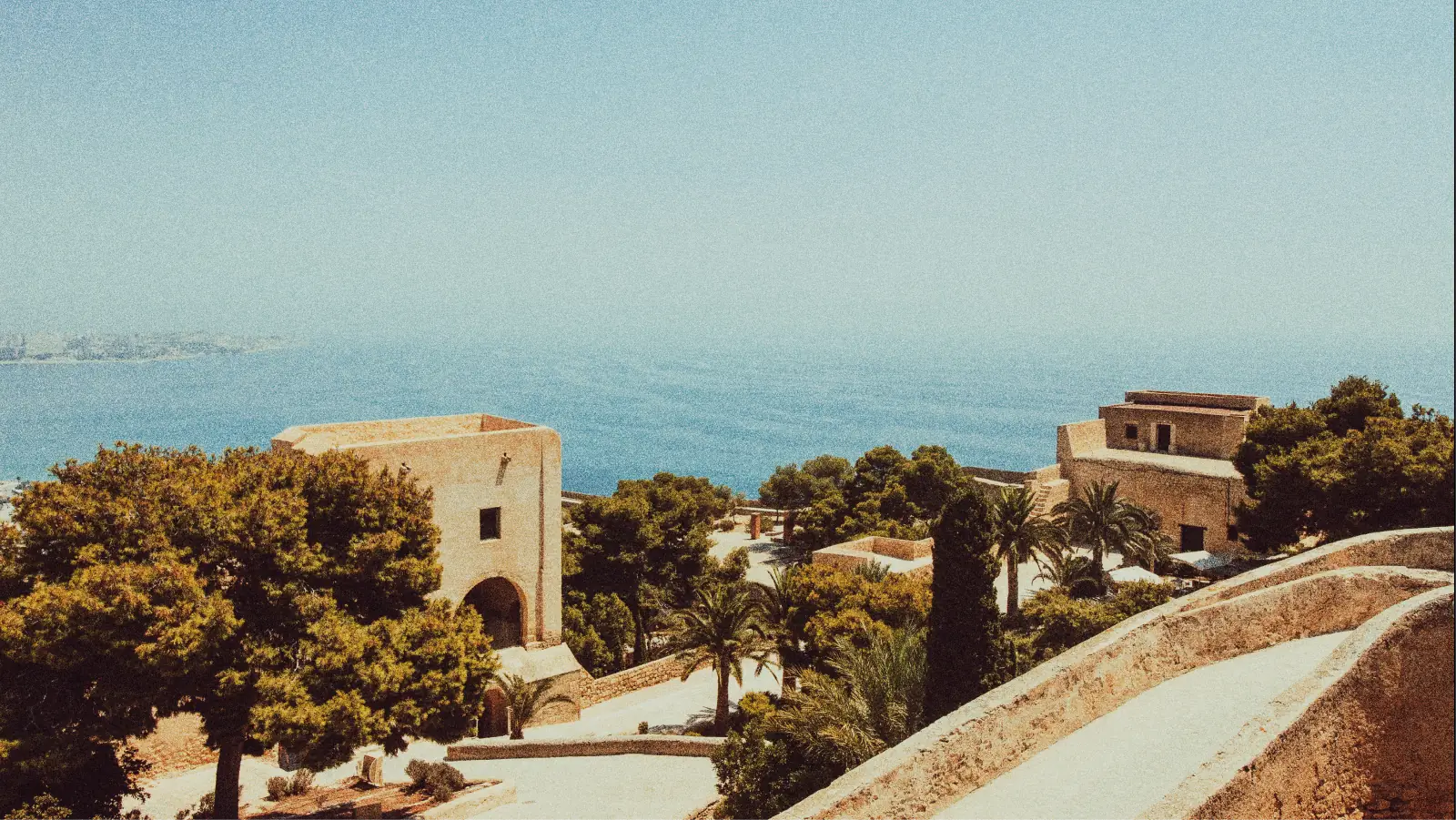 Mediterranean coastline with stone buildings, pines and palms