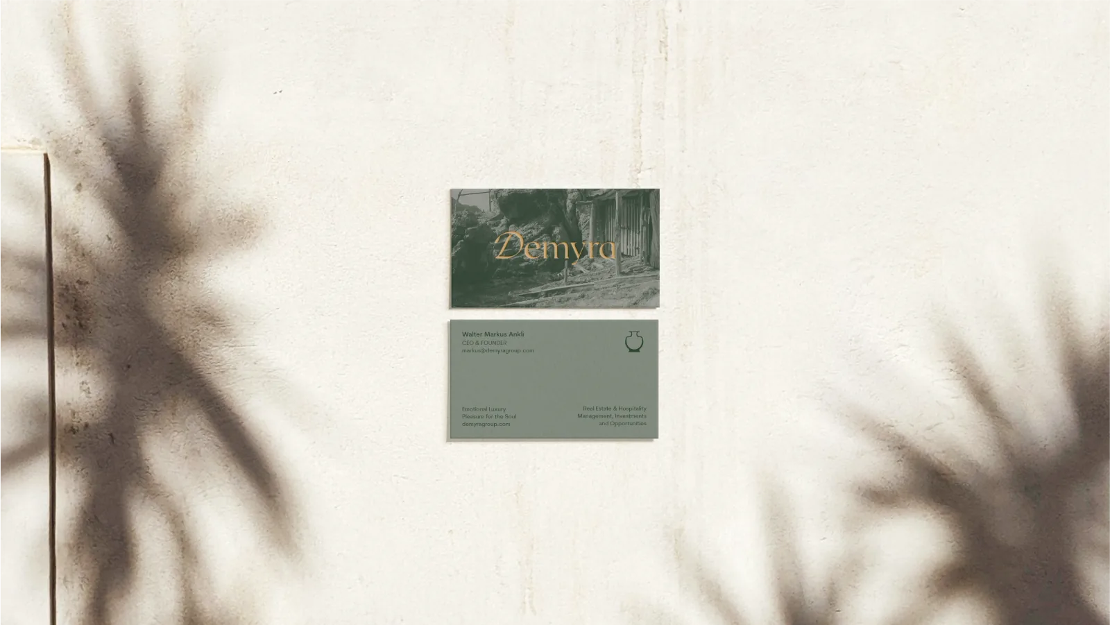 Gold-embossed business card front and back on a sunlit wall